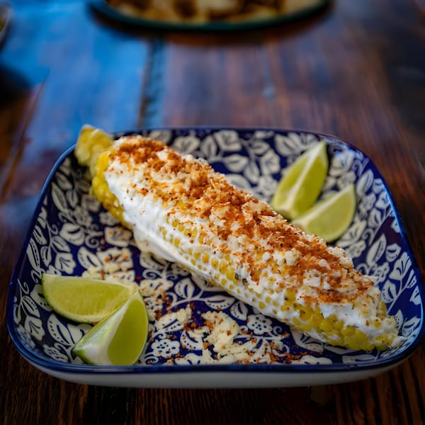 Hacienda Tacos' elote, grilled corn on the cob with crema, chili powder, and lime wedges.